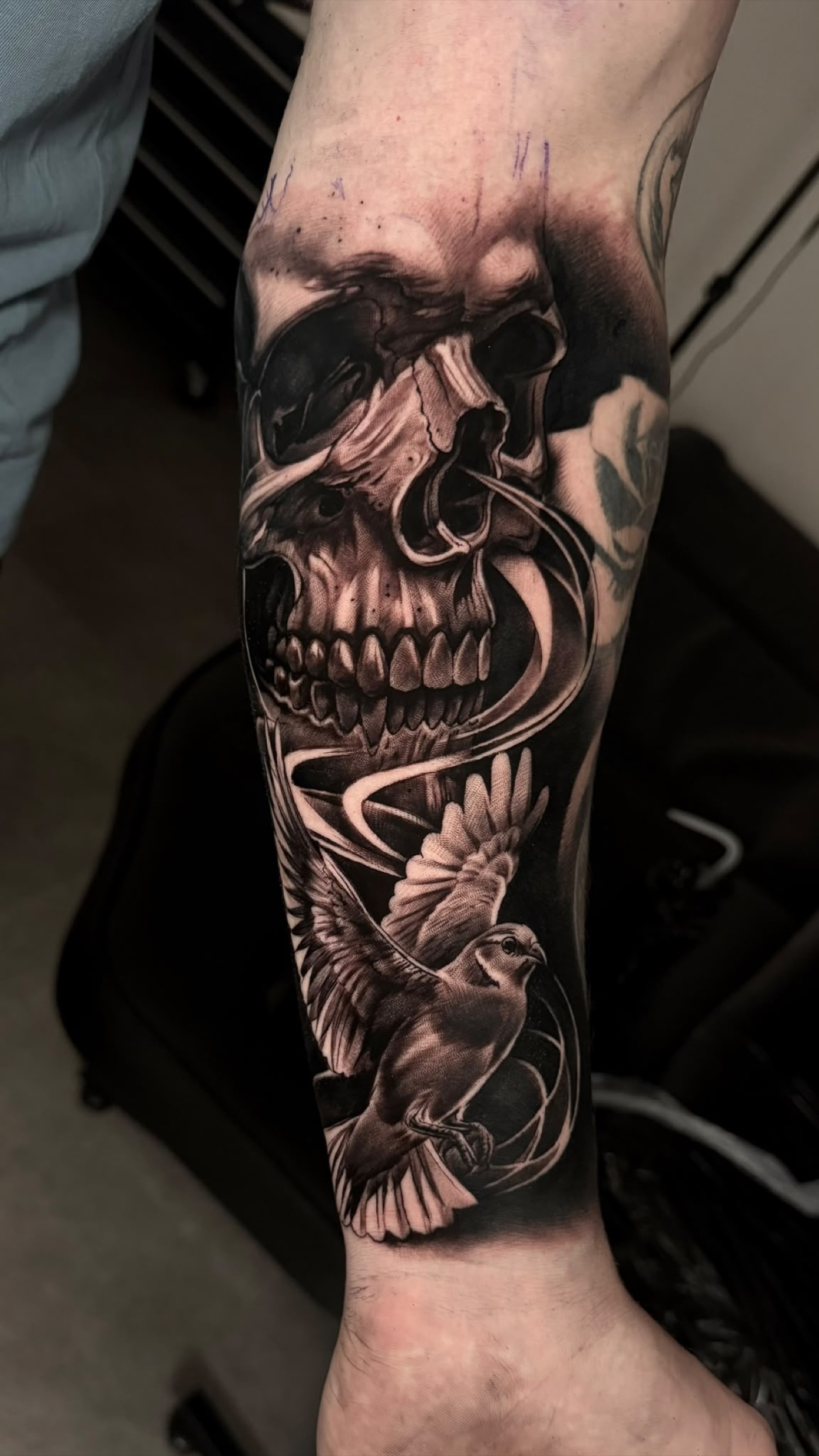 Black and grey skull and bird forearm tattoo